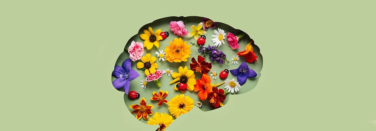 Paper cut brain and flowers on green background. Mental health concept
