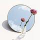 Dried pink peony flower in a clear vase reflected on a mirror