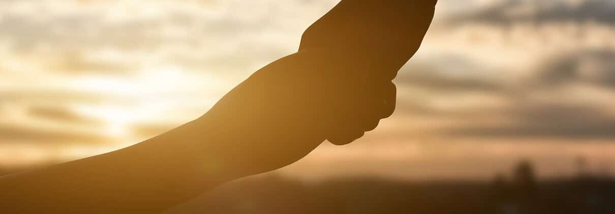 Silhouette of giving a help hand, hope and support each other over sunset background. Concept of helping hands and develop a friendship.