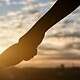 Silhouette of giving a help hand, hope and support each other over sunset background. Concept of helping hands and develop a friendship.