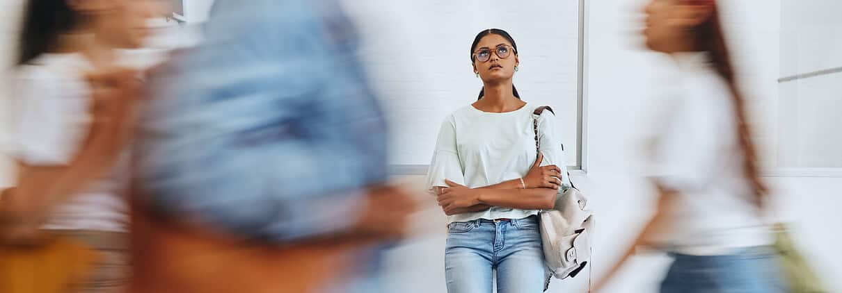 Overwhelmed young woman standing in busy crowd at mental health awareness event.