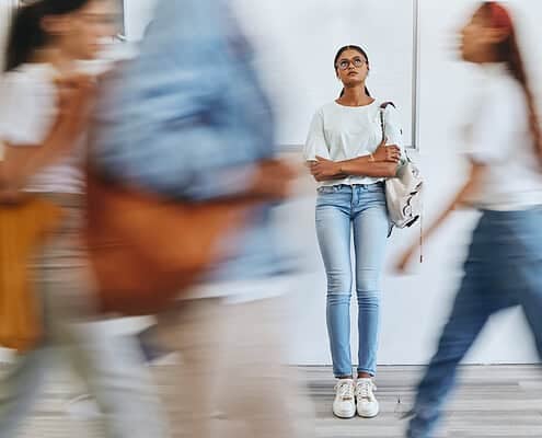Overwhelmed young woman standing in busy crowd at mental health awareness event.
