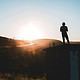 Silhouette of a person standing on a roof at sunset with mountains in the background.
