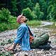 Relaxed man sitting by a creek in nature, highlighting mental health and outdoor therapy.