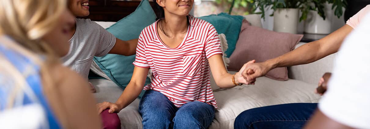 Supportive therapy session with diverse young women in a cozy living room.