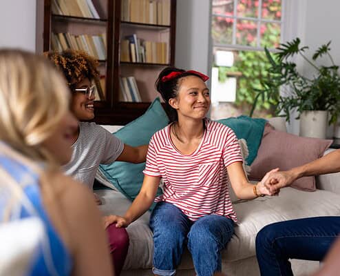 Supportive therapy session with diverse young women in a cozy living room.