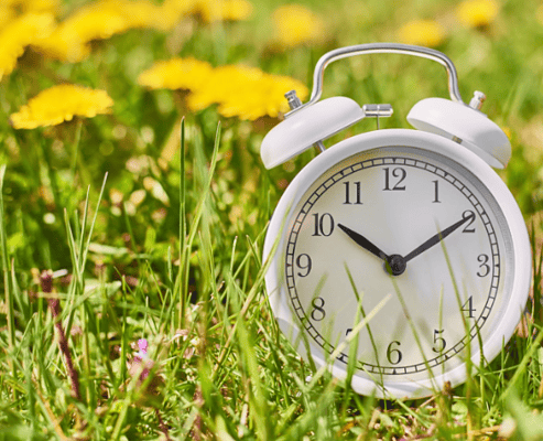 White alarm clock in grass, symbolizing time management challenges with ADHD.